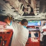 Mechanik naprawia podniesione Porsche w warsztacie samochodowym