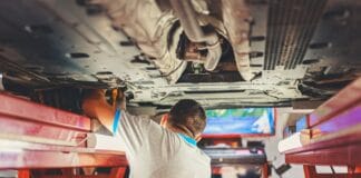 Mechanik naprawia podniesione Porsche w warsztacie samochodowym