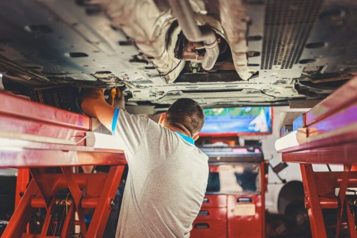 Mechanik naprawia podniesione Porsche w warsztacie samochodowym
