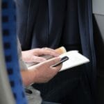 Osoba czyta książkę o podróżach, trzymając w dłoni smartfon