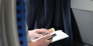 Osoba czyta książkę o podróżach, trzymając w dłoni smartfon