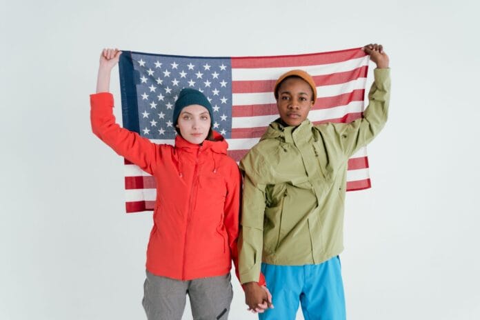 Dwoje młodych dorosłych pozuje z flagą USA w studiu Dwoje młodych dorosłych pozuje z flagą USA w studiu