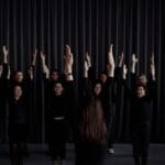 Młodzieżowa grupa teatralna ćwiczy scenę z uniesionymi ramionami