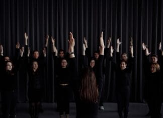 Młodzieżowa grupa teatralna ćwiczy scenę z uniesionymi ramionami