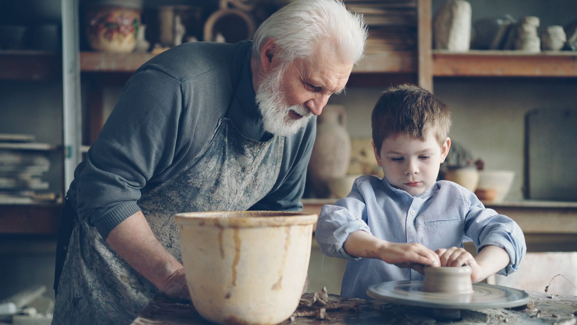 Senior i chłopiec wspólnie lepią ceramikę w pracowni