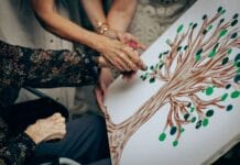 Senior i opiekun malują wspólnie obraz drzewa na płótnie