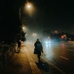 Nocna, słabo oświetlona ulica w mieście, przechodnie na chodniku