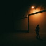 Sylwetka osoby pod latarnią na nocnej ulicy w mieście